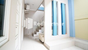 Un intérieur moderne avec un escalier menant à un deuxième étage, des murs blancs et un mur d’accent bleu.