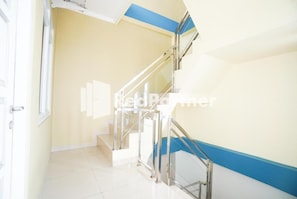 Eine Treppe mit Glastrennwand, beige Wänden und blauer Umrandung.