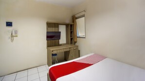 A hotel room with a bed, a desk, a chair, a television, and a telephone. - OYO 3754 Prosperity Mansion (Jakarta)