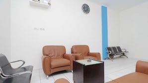 A waiting area with leather chairs, a coffee table, and a clock on the wall. - OYO 3754 Prosperity Mansion (Jakarta)
