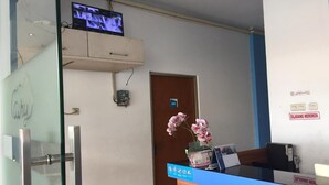 A reception area with a blue counter, a television mounted on the wall, a door with a sign, and a flower vase. - OYO 3754 Prosperity Mansion (Jakarta)