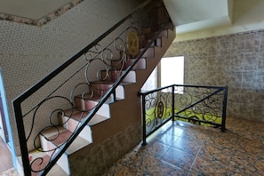 A staircase with ornate metal railings, patterned walls, and tiled flooring. - Potreh Mastekah 2 (Bangkalan)