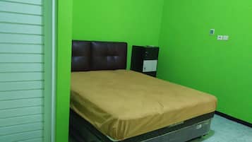 Una stanza con un letto, una parete verde e una porta chiusa.