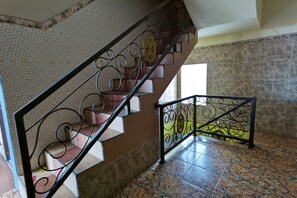 A staircase with ornate metal railings, patterned walls, and tiled flooring. - Potreh Mastekah 2 (Bangkalan)