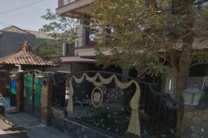 Zona residencial con entrada protegida por un muro, techo de tejas y un árbol.