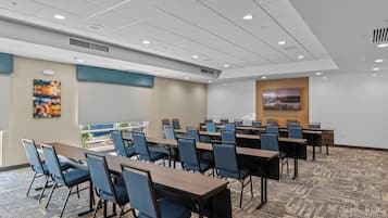 A conference room with multiple tables and chairs, a projector screen, and a large window with a view.