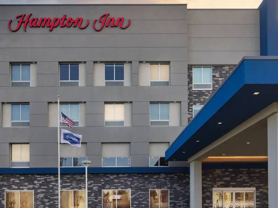 A Hampton Inn hotel with a modern facade, multiple windows, and an American flag.