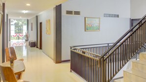 Ein Hotelkorridor mit Treppe, einem Essbereich mit Stühlen und Tisch sowie Kunstwerken an den Wänden.
