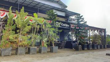 A coffee shop with outdoor seating and potted plants.