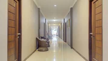 A hallway with wooden doors, a seating area with chairs, and a tiled floor.