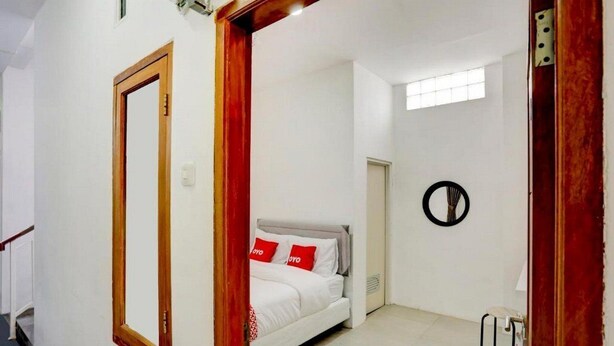 A bedroom with a bed, a mirror, a door, and a window. - OYO 4009 Jabusimo Syariah (Jakarta)