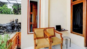 A room with two wooden chairs, a small table with a laptop, and a window with a view of parked motorcycles outside. - OYO 4009 Jabusimo Syariah (Jakarta)