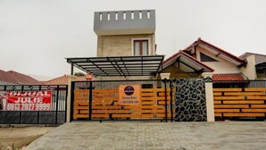 A gated residential property with a stone facade, a small tower-like structure, and a signboard advertising a real estate service. - OYO 4009 Jabusimo Syariah (Jakarta)