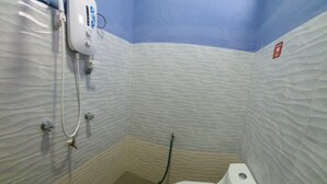 A small bathroom with a white toilet, a hand dryer, and a showerhead mounted on the wall. - Hotel O Penginapan Wahee (Kuala Terengganu)