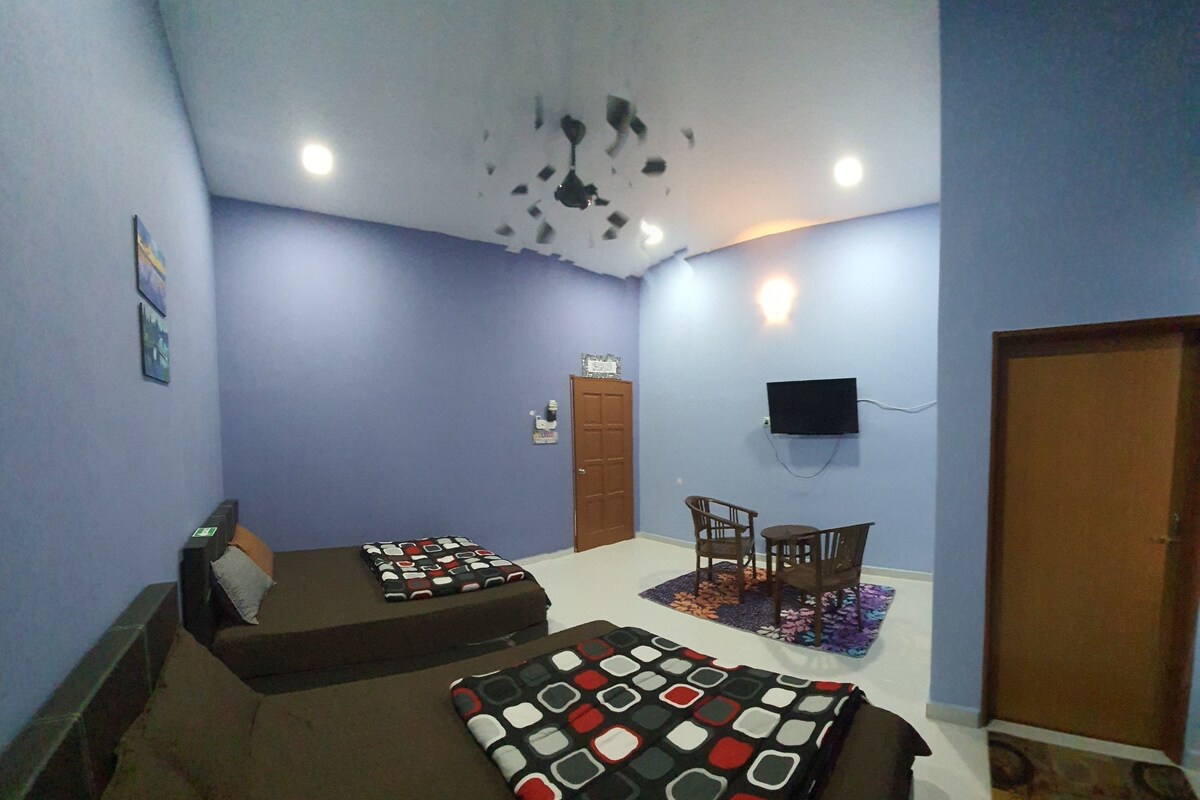 A room with two beds, a TV mounted on the wall, and a door.