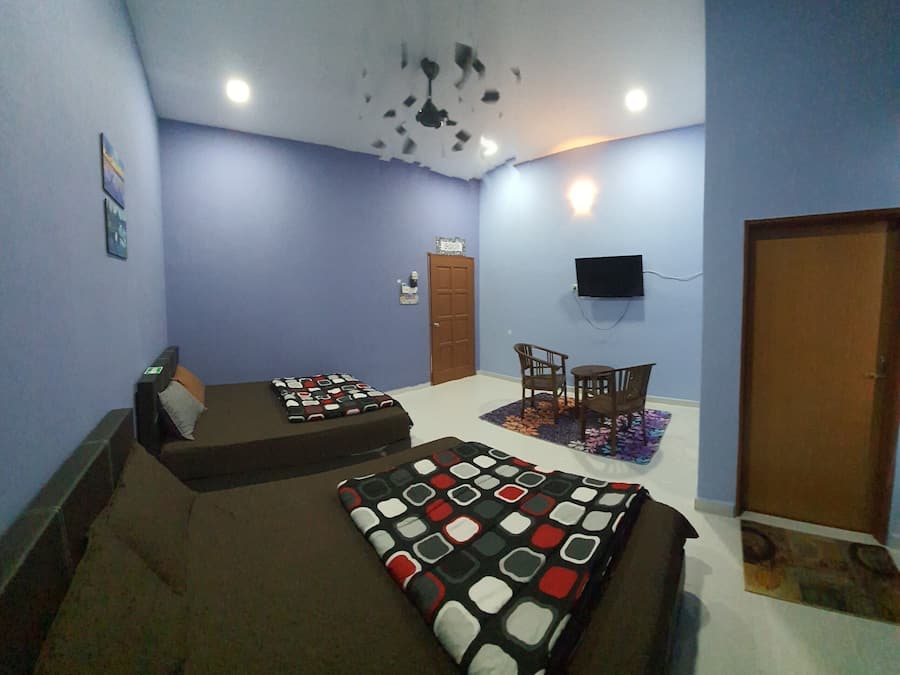 A bedroom with two beds, a desk, a chair, a television, and a door.