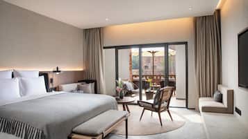 Een moderne hotelkamer met een groot bed, een bank, een eettafel en uitzicht naar buiten.