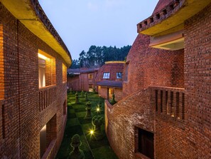 A courtyard with brick buildings, a central lawn, and a small tree. - Dongfengyun Hotel Mi'le-mgallery Collection (Honghe)