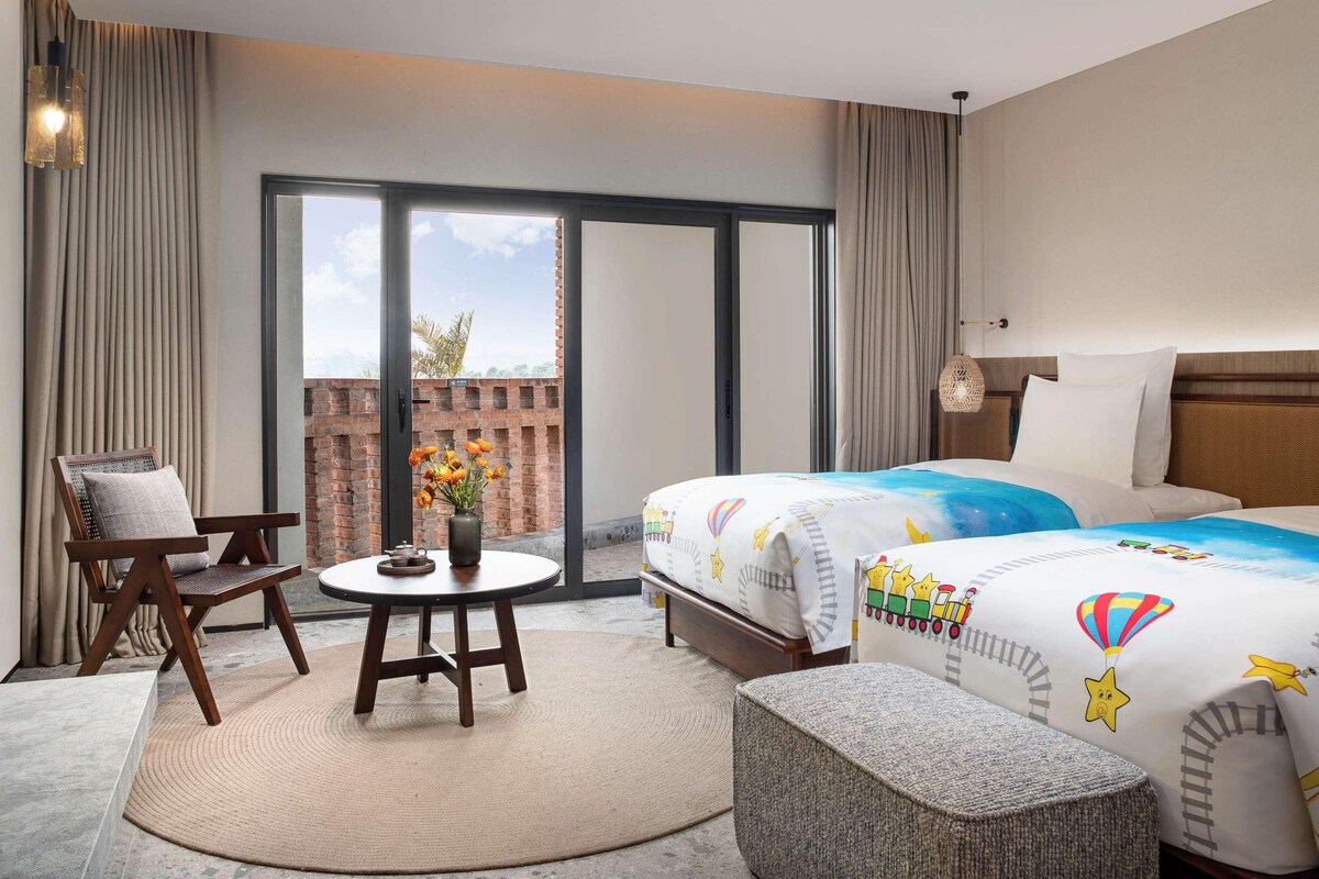 Une chambre d’hôtel comprenant un lit, deux tables de chevet, une chaise, une table ronde et une vue sur l’extérieur.