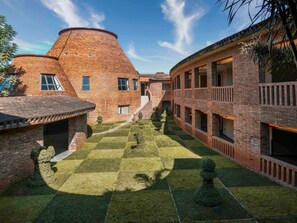 Une cour avec un bâtiment en briques, une structure en forme de dôme et une pelouse bien entretenue.
