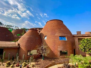 A building with unique conical brick structures, surrounded by cacti and ferns. - Dongfengyun Hotel Mi'le-mgallery Collection (Honghe)