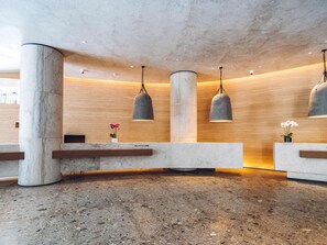 Un espace d’accueil doté de colonnes en marbre, d’un comptoir de réception et d’un éclairage suspendu.