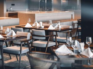 Un restaurante moderno con mesas dispuestas para comer, con sillas acolchadas y servilletas ordenadas.