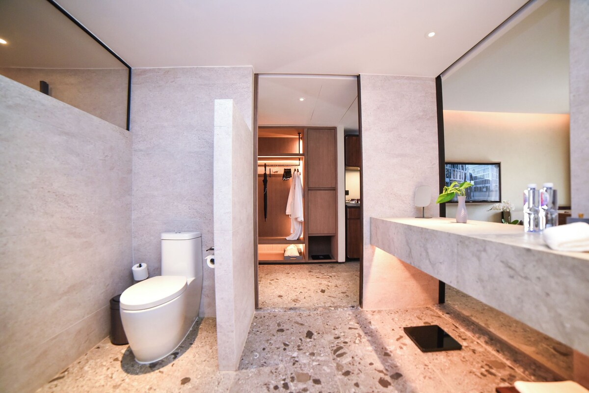 Un bany modern amb sòl de marbre, un vàter, un lavabo amb mirall i una zona de dutxa.