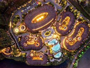 Vista aérea de un resort con varias estructuras circulares, caminos serpenteantes y zonas ajardinadas.