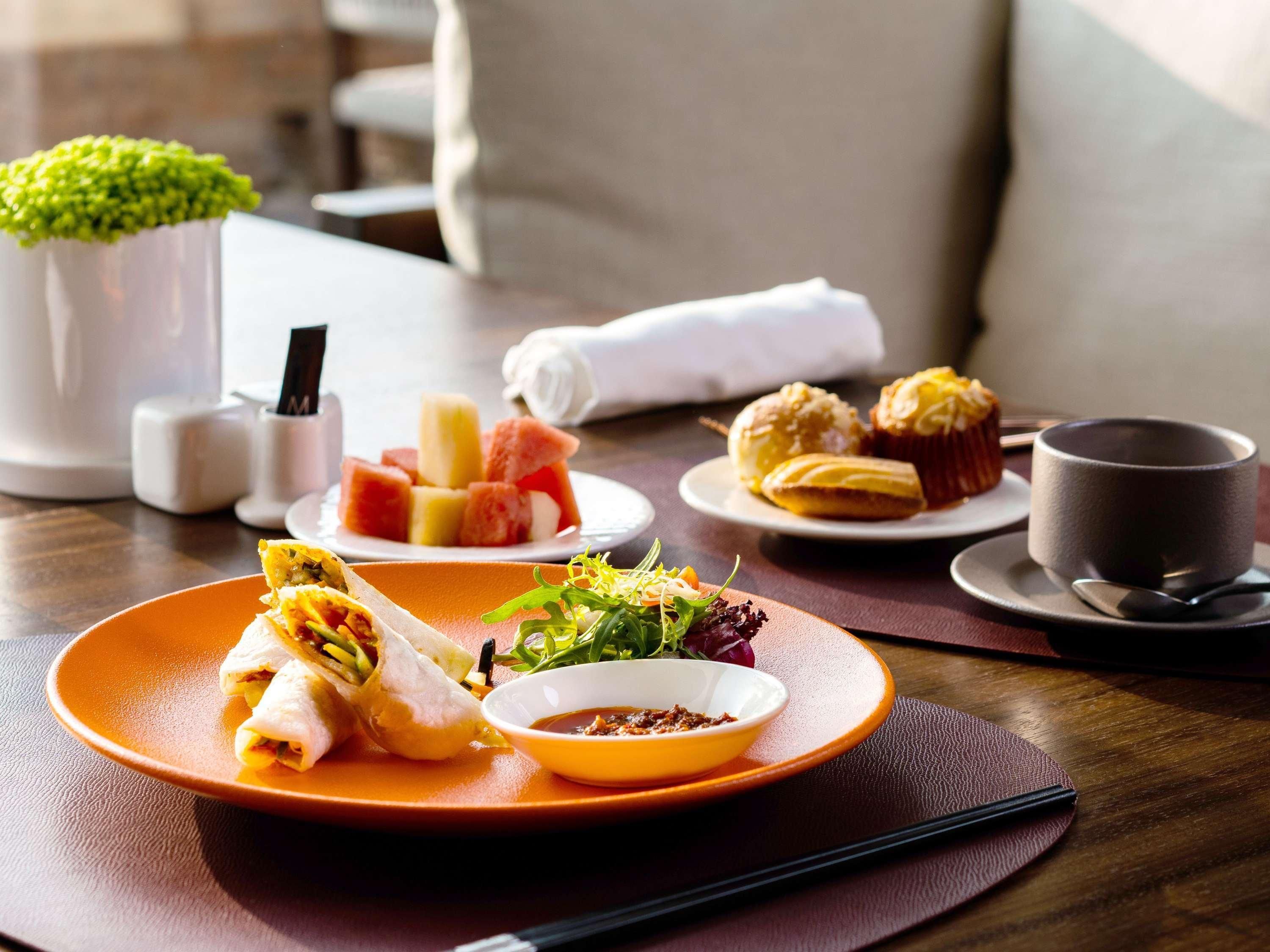 Una mesa de comedor con platos de comida, una taza y un recipiente pequeño con salsa.