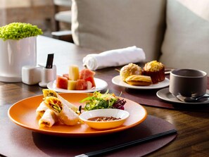 A dining table with plates of food, a cup, and a small bowl of sauce. - Dongfengyun Hotel Mi'le-mgallery Collection (Honghe)
