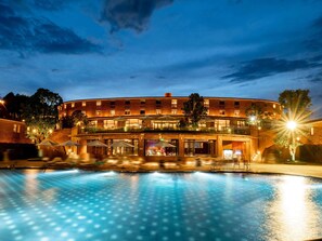 Een hotel met een zwembad, terras en een gevel van baksteen.
