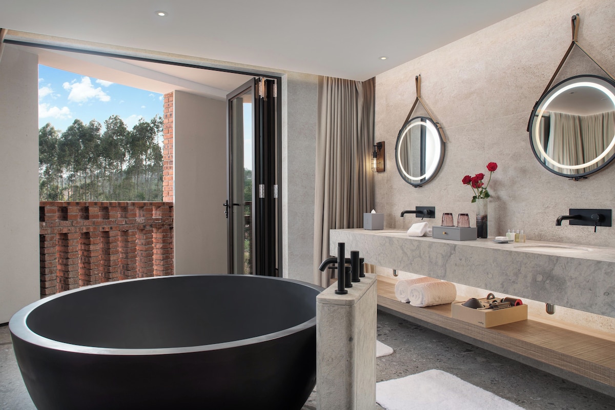 Un baño moderno con una bañera independiente, un espejo grande y un tocador con encimera de mármol.