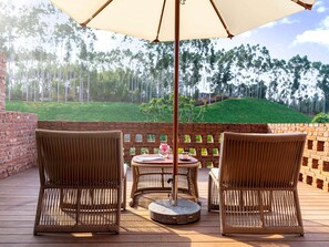 A patio with wicker chairs, a round table, and a large umbrella. - Dongfengyun Hotel Mi'le-mgallery Collection (Honghe)