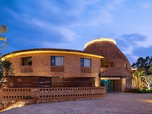 Un edificio de ladrillo con fachada curva, una estructura en forma de cúpula y una entrada porticada.