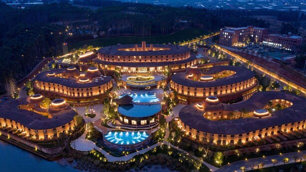 Un gran complejo hotelero circular con varios edificios redondos, una piscina central y zonas ajardinadas alrededor.