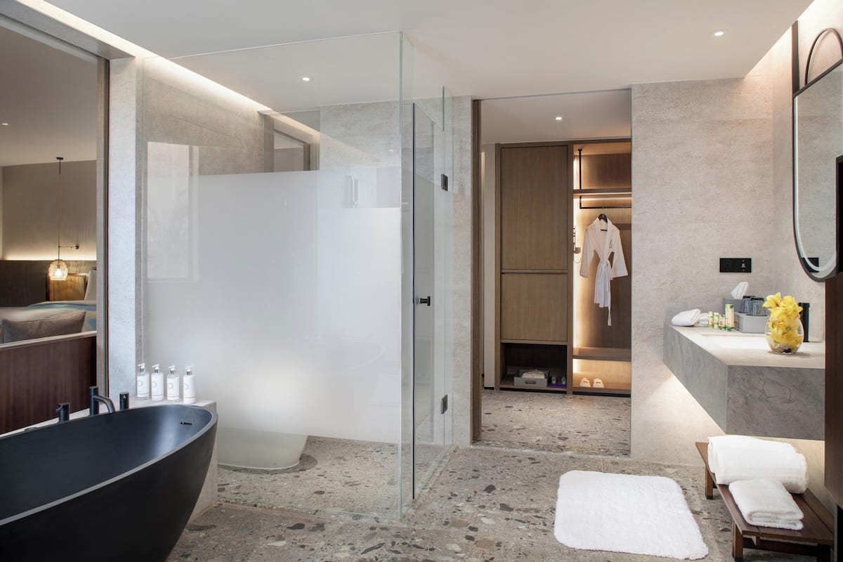A modern bathroom with a large bathtub, glass shower enclosure, and a vanity with toiletries.