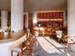 A bar area with a counter, bar stools, and a wall of bottles. - Dongfengyun Hotel Mi'le-mgallery Collection (Honghe)