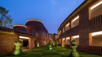 A courtyard with brick buildings, a circular structure, and topiary garden features.