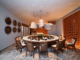 A round dining table with chairs, overhead lighting, and a wooden partition wall.