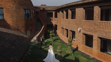Un patio con un edificio de ladrillo, una escalera y una novia con un vestido blanco.