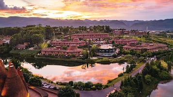 Un hotel con un patio circular, un lago y montañas al fondo.