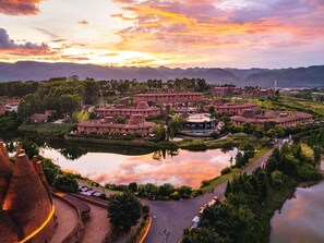 A hotel with a circular courtyard, a lake, and a mountain backdrop.