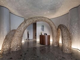 Vestíbulo con diseño moderno, que incluye un mostrador de recepción y una estructura de arco tejido único.