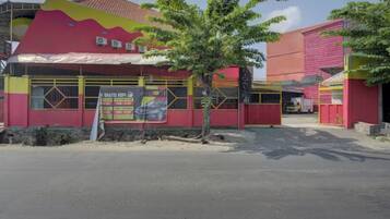 A building with a red and yellow facade, a tree in front, and a signboard.