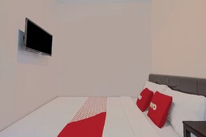 A modern hotel room with a flat-screen TV mounted on the wall, a neatly made bed with white and red bedding, and a grey headboard. - Super OYO 3198 Sukomanunggal Inn (Surabaya)