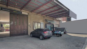 Un edificio con un letrero que dice 'Welcome Auto Bridal Club', un coche estacionado y una zona cubierta con un vehículo azul.