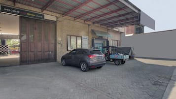 A building with a sign reading 'Welcome Auto Bridal Club,' a parked car, and a covered area with a blue vehicle.