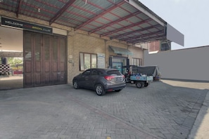 A building with a sign reading 'Welcome Auto Bridal Club,' a parked car, and a covered area with a blue vehicle. - Super OYO 3198 Sukomanunggal Inn (Surabaya)