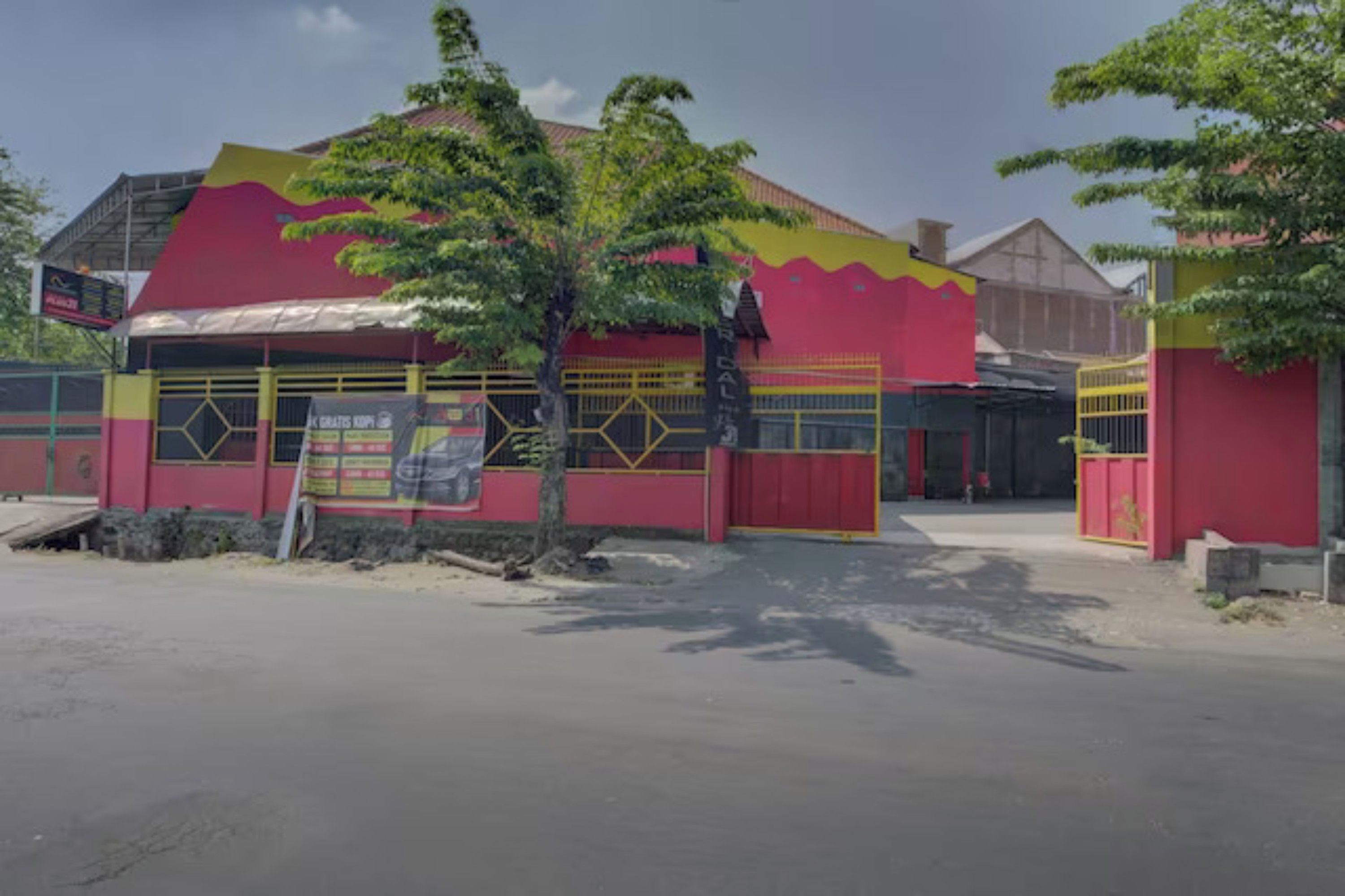 Un edificio con fachada roja y amarilla, un vestíbulo cubierto y un cartel.